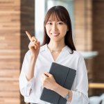 iPadを抱えて人差し指を立てる女性、白いワイシャツの女性