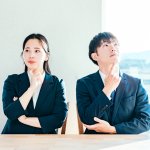 斜め上を見て考える男女2人、スーツ、悩む