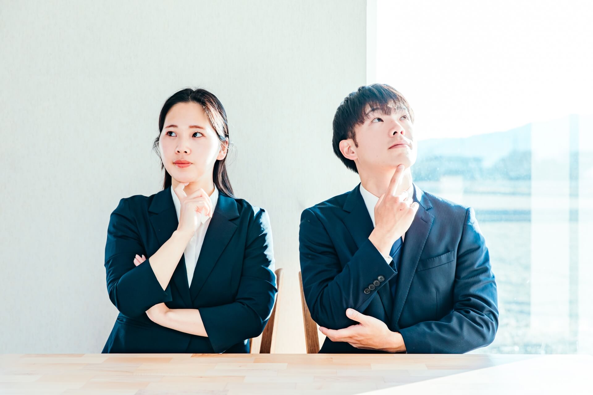 斜め上を見て考える男女2人、スーツ、悩む