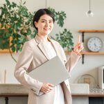 ノートPCを持って人差し指を立てる女性、オフィス