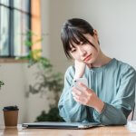 スマホを片手に悩む女性