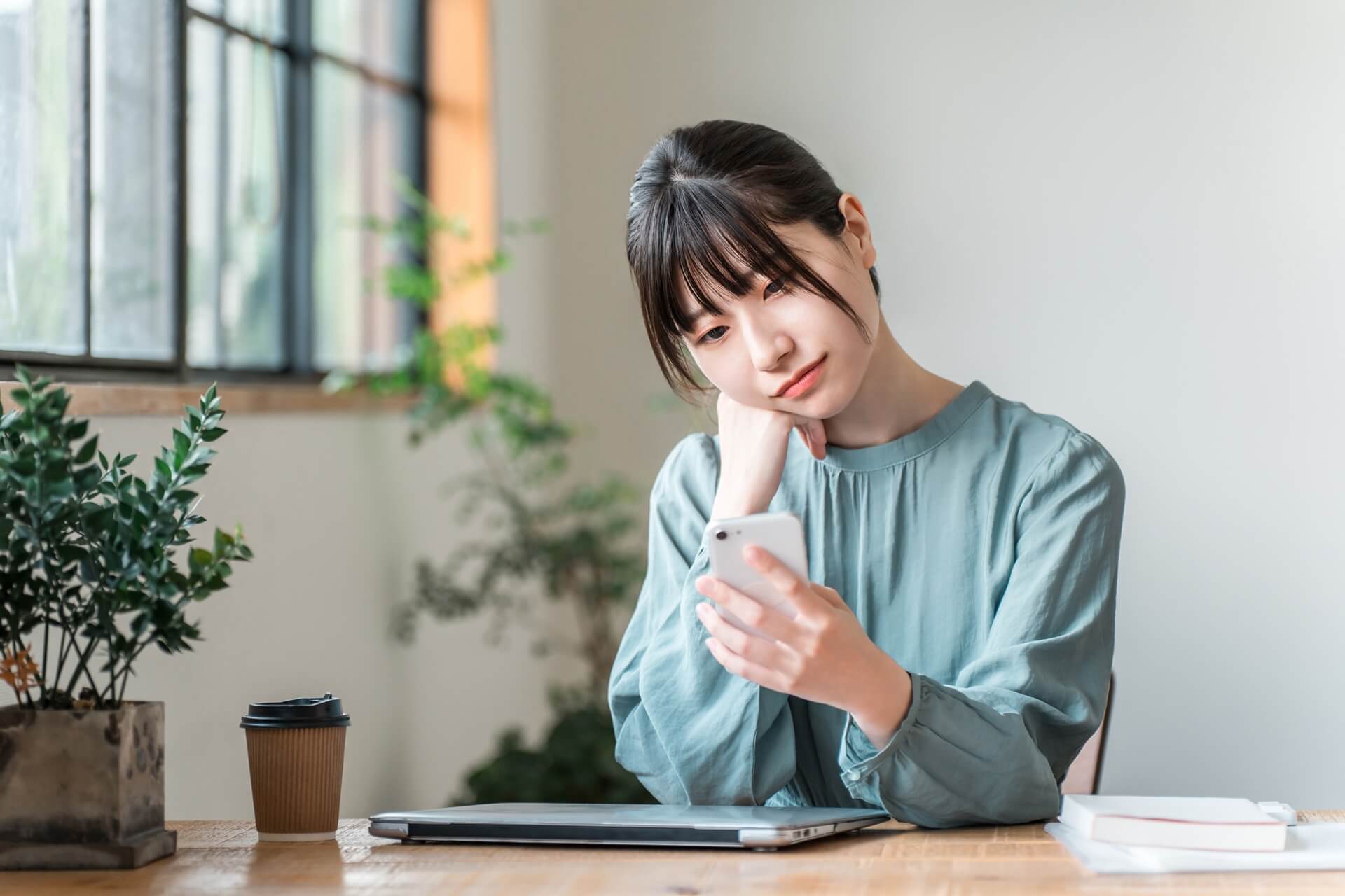 スマホを片手に悩む女性