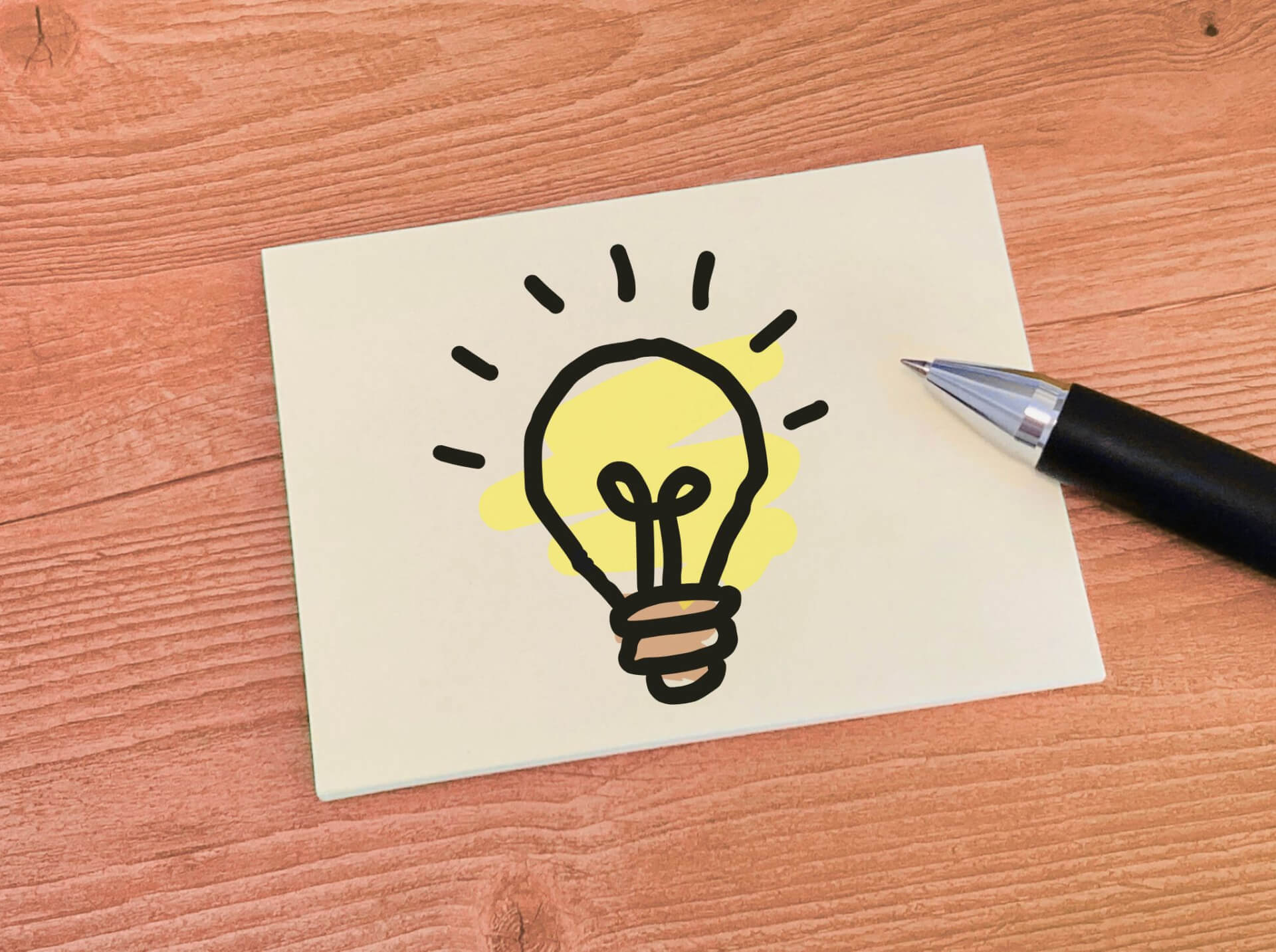 ポイント、ひらめき、電球が描かれたメモとペン
