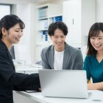 ノートPCを笑顔で見るスーツの女性と若い男女