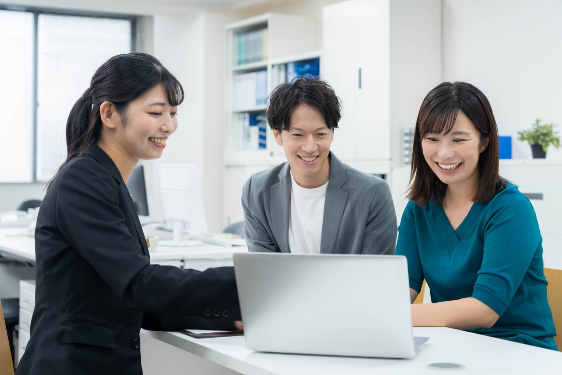 ノートPCを笑顔で見るスーツの女性と若い男女